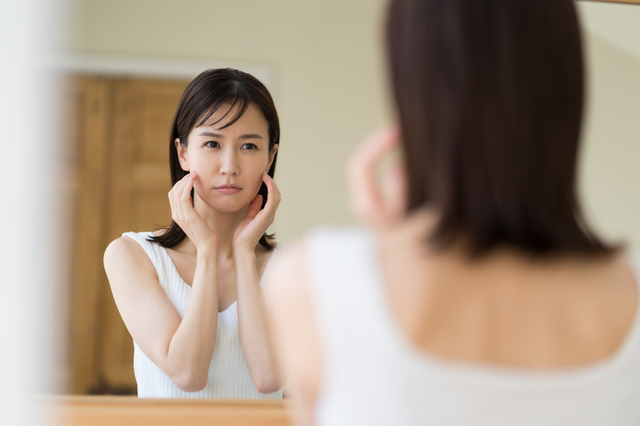鏡を見てショックを受ける女性